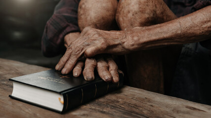 Oldmans hands together in prayer to God along with the bible In the Christian concept and religion, woman pray in the Bible