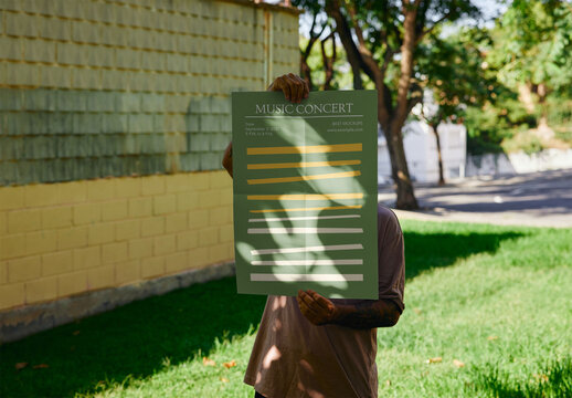 Man Holding An A2 Vertical Poster Mockup In A Park