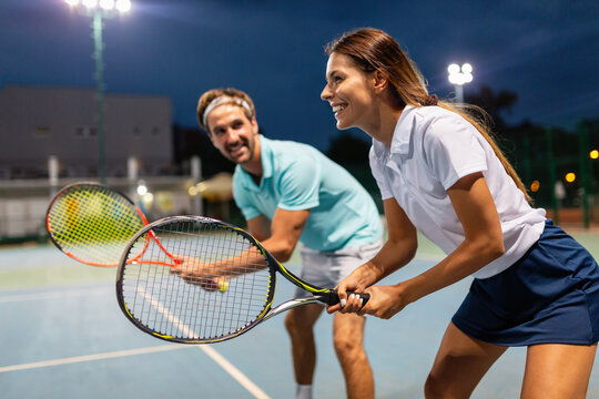Young couple on tennis court. Handsome man and attractive woman are playing tennis.