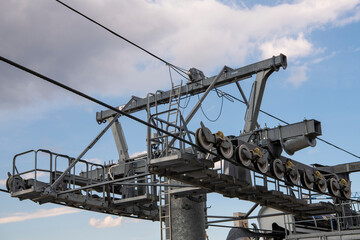 Cable car machinery mechanism mounted high above mountain,  farmlands below. Metal cable and moving rollers on platform for funicular mechanism. Mountain Zlatibor, Serbia