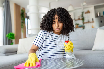 Woman cleaning and polishing the table with a spray detergent, housekeeping and hygiene concept