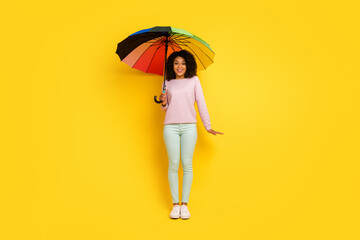 Full size photo of young cheerful lady hold parasol walk weather rainy isolated over yellow color background © Tetiana