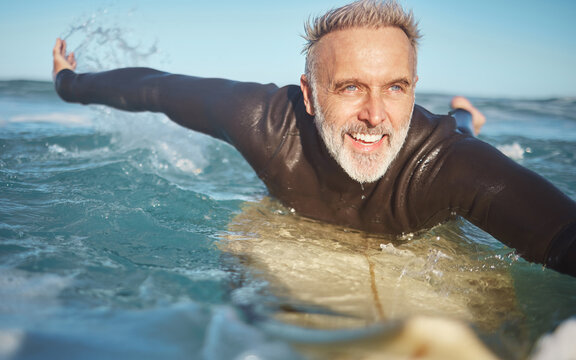 Beach, water and old man surfer swimming on a summer holiday vacation in retirement with freedom in Bali. Smile, ocean and senior surfing or body boarding enjoying a healthy exercise on sea of Island - Powered by Adobe
