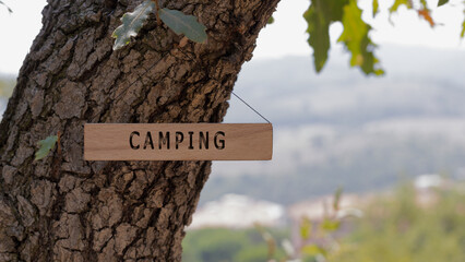 camping. Written on wooden surface. Background tree leaves. health and sport