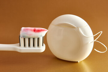 Toothbrush with toothpaste and dental floss on a golden background. Dental care. Oral hygiene.