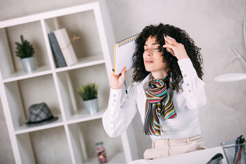 Exhausted businesswoman with headache touching her head while sitting at office