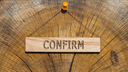 Confirm. Written on wooden hanging frame. Background wood cut log.