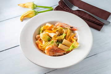 Piatto di saporita pasta con gamberi e fiori di zucca, cibo italiano 