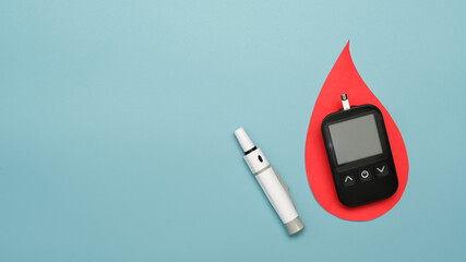 A glucometer and lancet pen on blue background with copy space. Diabetes and health care concept