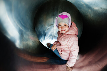 Baby girl ride down the steel tube slide.