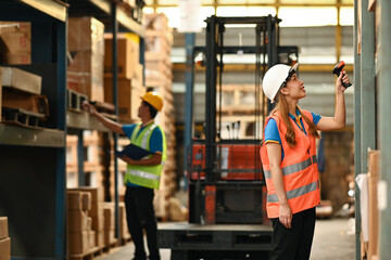 Young female warehouse worker using barcode scanner checking stock on shelves in a warehouse