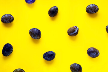 Image of big plums on a yellow background, ripe plums scattered on a yellow background