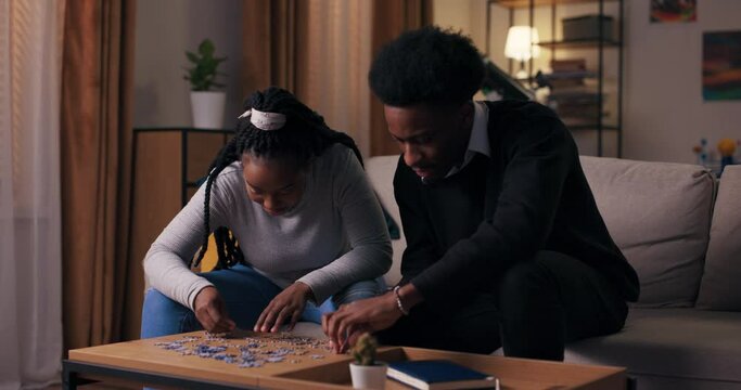 A couple in love likes to spend time together and collect puzzles. For girl of African appearance with long hair, this is favorite hobby. Her boyfriend also likes this activity. Together they talk.