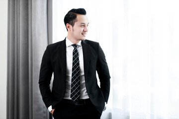 Business handsome man worker in black suit standing in window office glass.