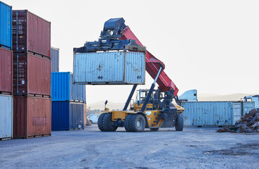 Logistics, cargo and forklift with container with stock for delivery in an industrial port. Ecommerce worker working with transportation of manufacturing product with a crane at an outdoor warehouse