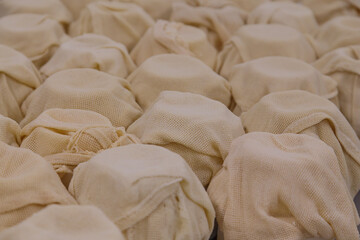 Wheels of the cheese in cheesecloth.