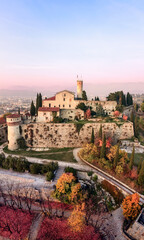 Fototapeta premium Vertical panoramic drone view on eastern part of castle in Brescia and surrounding park with trees and bushes of various autumn colors. Brescia, Lombardy, Northern Italy
