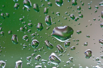 Close up von freigestellten Wassertropfen auf einer Fensterscheibe mit grünem Hintergrund