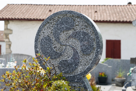 St&egrave;le disco&iuml;dale en pierre avec une croix basque dans un cimeti&egrave;re, au Pays Basque