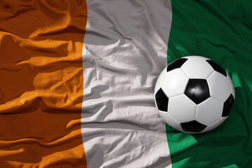 vintage football ball on the waveing national flag of cote divoire background. 3D illustration