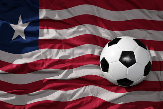 vintage football ball on the waveing national flag of liberia background. 3D illustration