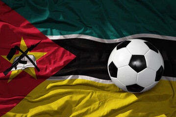 Naklejka premium vintage football ball on the waveing national flag of mozambique background. 3D illustration