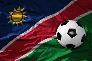 Naklejka premium vintage football ball on the waveing national flag of namibia background. 3D illustration