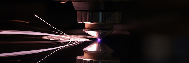 Laser machine cutting sheet of metal with bright sparks closeup