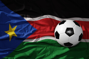 vintage football ball on the waveing national flag of south sudan background. 3D illustration