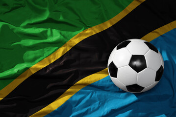 vintage football ball on the waveing national flag of tanzania background. 3D illustration