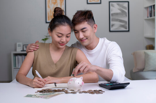 Young happy Asian couple saving money to buy a house. Man and Women couple saving money for family and home.