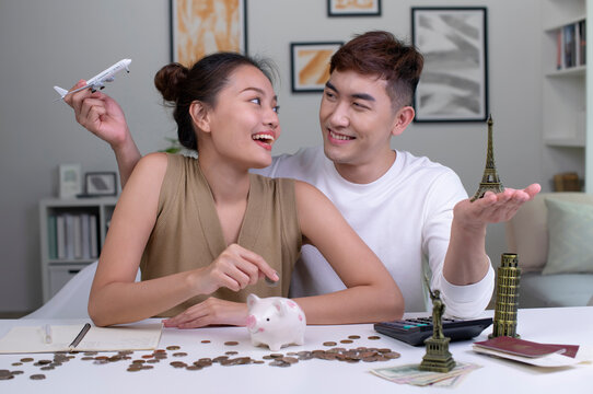 Young Asian couple plans to save money for a trip around the world. Travel budget concept. passport, monument model and aircraft toy in the picture.