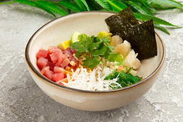 Poke with tuna and avocado in a plate on a gray background.