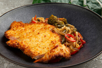 Fried chicken and wok noodles in a plate. on a gray background.