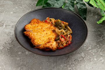 Fried chicken and wok noodles in a plate. on a gray background.