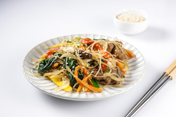 Japchae is Korean traditional dish, stir-fried Korean vermicelli noodles with vegetables and slices beeef, topping with sesame seeds.