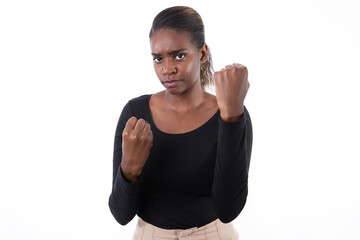 Portrait of aggressive African American woman with clenched fists. Angry young model in black shirt with ponytail looking at camera, ready to fight. Anger, fight concept.