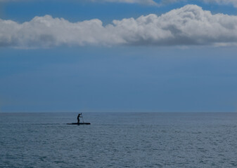 person practicing paddle surfing in the calm sea