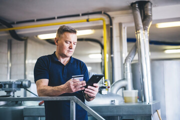 Craft brewery owner or manager paying with mobile phone
