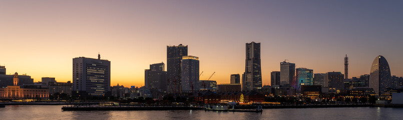 Fototapeta premium Wide panorama of Yokohama Minato Mirai 21 seaside urban area in Japan at golden hour.