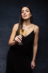 Holidays - A young woman in a black dress with a glass of champagne.