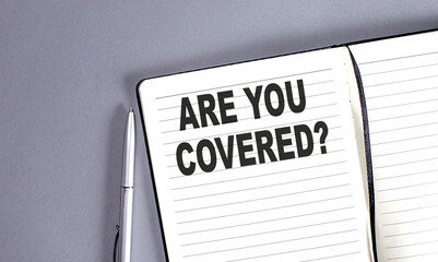 ARE YOU COVERED word on the notebook with pen