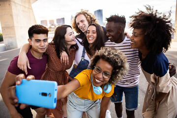 Group of happy young people taking selfie portrait together on summer vacation - Cheerful multiracial best student friends laughing and having fun after school classes - Community concept