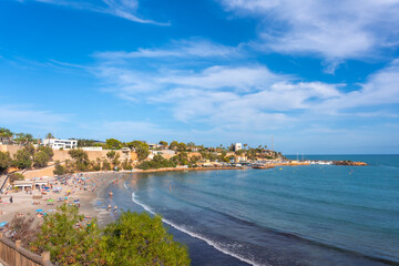 La Caleta beach full of tourists in the tourist town of Cabo Roig. Alicante - obrazy, fototapety, plakaty