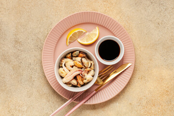 Mix of sea food - mussels, squid, octopus, shrimp in a bowl, lemon and soy sauce. Top view.