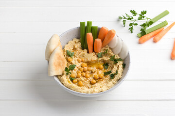 Traditional classic hummus with cumin, parsley, olive oil, served with vegetables and pita bread on...