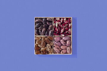 Set of organic beans in a wooden box on a blue background. Scarlet runner, anasazi beans. Top view....