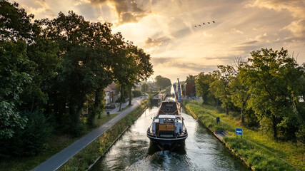 Aerial view of a colourful dramatic sunrise sky over a canal with a cargo boat in Belgium. Canals...