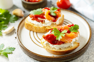 Fototapeta na wymiar Open sandwiches or bruschetta with salted salmon, cheese and sun dried tomato on a stone table. Healthy food, seafood.