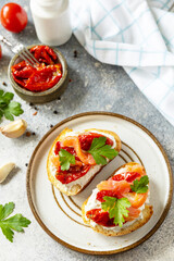 Open sandwiches or bruschetta with salted salmon, cheese and sun dried tomato on a stone table. Healthy food, seafood.